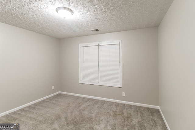 empty room with a textured ceiling and carpet flooring