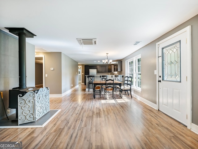 dining area with a wood stove, a notable chandelier, and light hardwood / wood-style flooring