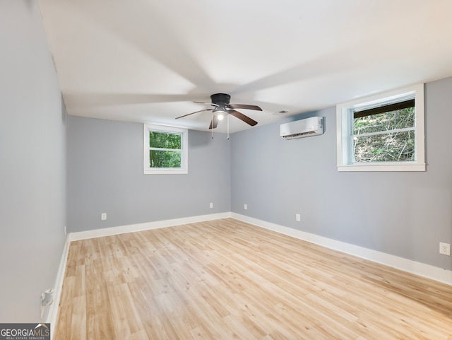 empty room featuring ceiling fan, light hardwood / wood-style floors, plenty of natural light, and a wall mounted air conditioner