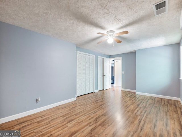 unfurnished room with ceiling fan, a textured ceiling, and light wood-type flooring