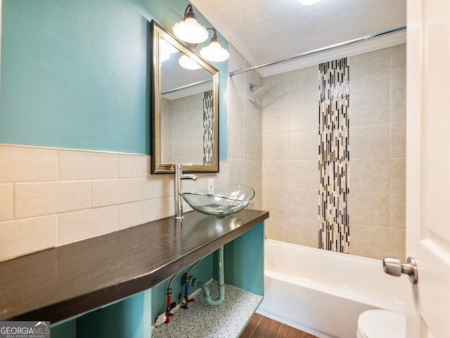 full bathroom featuring toilet, wood-type flooring, crown molding, tile walls, and tiled shower / bath