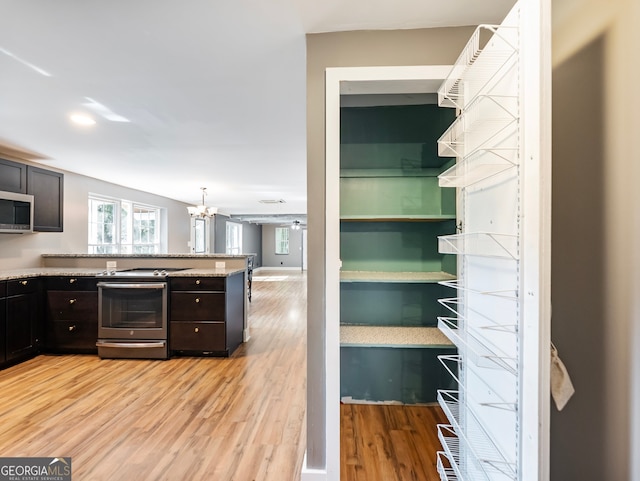 kitchen featuring appliances with stainless steel finishes, a notable chandelier, dark brown cabinetry, and light hardwood / wood-style flooring