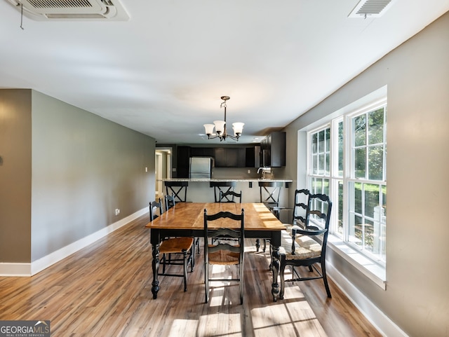 dining area with sink, a chandelier, light hardwood / wood-style floors, and a wealth of natural light