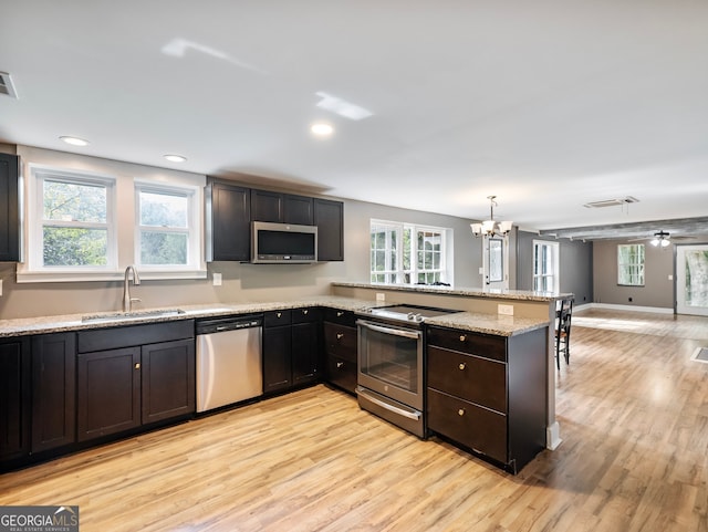 kitchen featuring stainless steel appliances, plenty of natural light, sink, and light hardwood / wood-style flooring