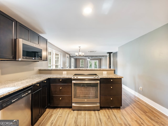 kitchen with appliances with stainless steel finishes, kitchen peninsula, and light hardwood / wood-style flooring