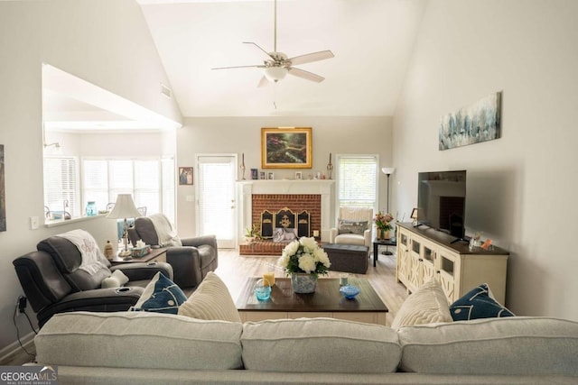 living room featuring hardwood / wood-style flooring, ceiling fan, high vaulted ceiling, and a brick fireplace