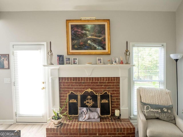 living area with wood-type flooring and a brick fireplace