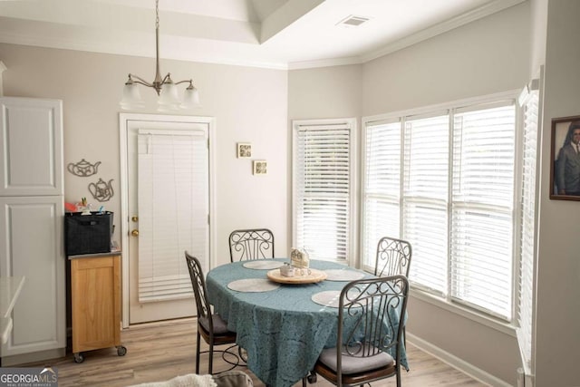 dining room with an inviting chandelier, ornamental molding, and light hardwood / wood-style flooring