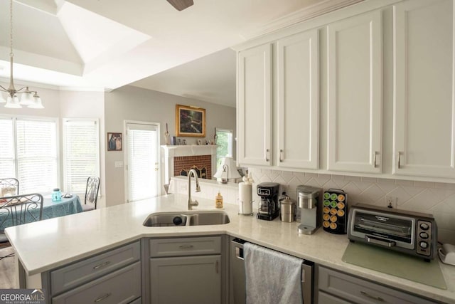 kitchen featuring dishwasher, sink, kitchen peninsula, pendant lighting, and decorative backsplash