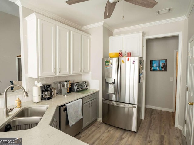 kitchen featuring white cabinetry, sink, stainless steel appliances, and ornamental molding