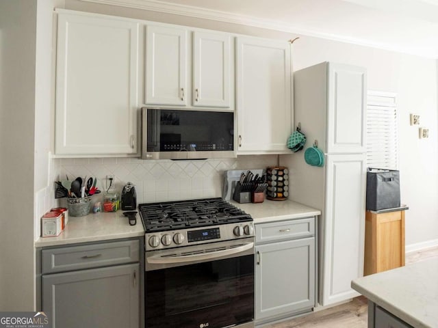 kitchen featuring gray cabinets, white cabinetry, appliances with stainless steel finishes, and tasteful backsplash