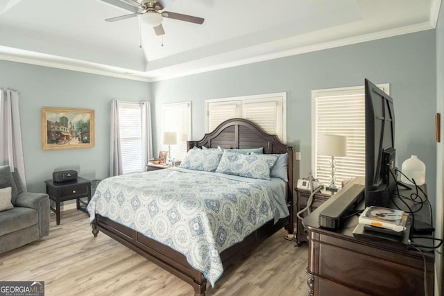 bedroom with a tray ceiling, ceiling fan, light hardwood / wood-style floors, and ornamental molding