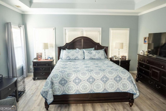 bedroom featuring a tray ceiling, light hardwood / wood-style floors, and ornamental molding