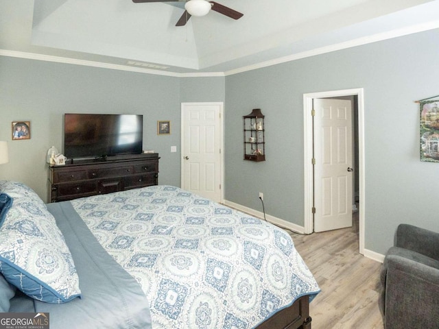 bedroom with a raised ceiling, ceiling fan, crown molding, and light wood-type flooring