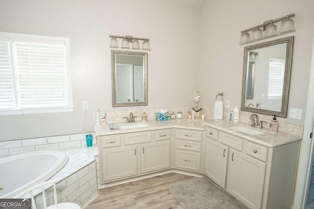 bathroom featuring a wealth of natural light, vanity, hardwood / wood-style flooring, and a relaxing tiled tub