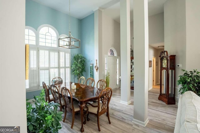 dining room with a wealth of natural light, light hardwood / wood-style floors, a high ceiling, and a chandelier