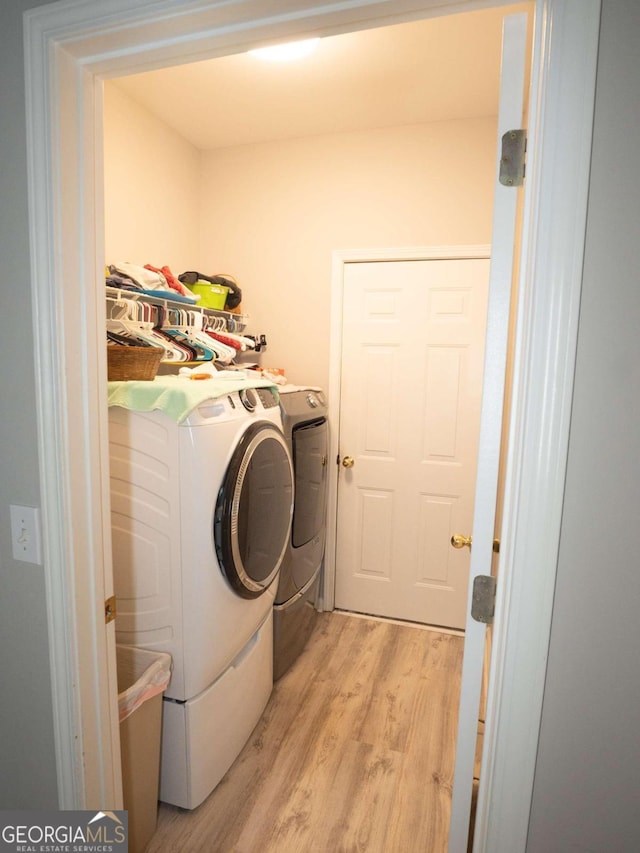 laundry room with independent washer and dryer and light hardwood / wood-style flooring