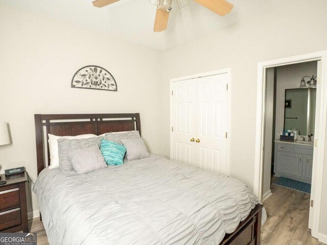 bedroom featuring sink, light hardwood / wood-style flooring, ceiling fan, connected bathroom, and a closet