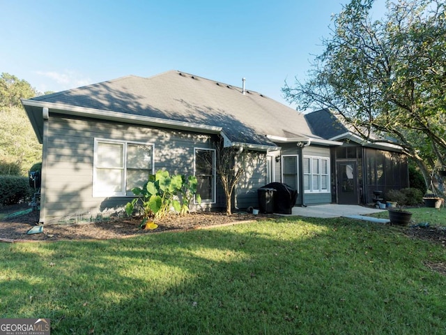 rear view of house with a yard and a sunroom