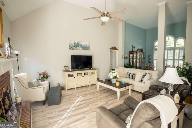 living room with ceiling fan, a fireplace, high vaulted ceiling, and light hardwood / wood-style flooring