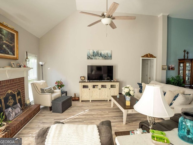 living room with hardwood / wood-style flooring, a brick fireplace, ceiling fan, and lofted ceiling