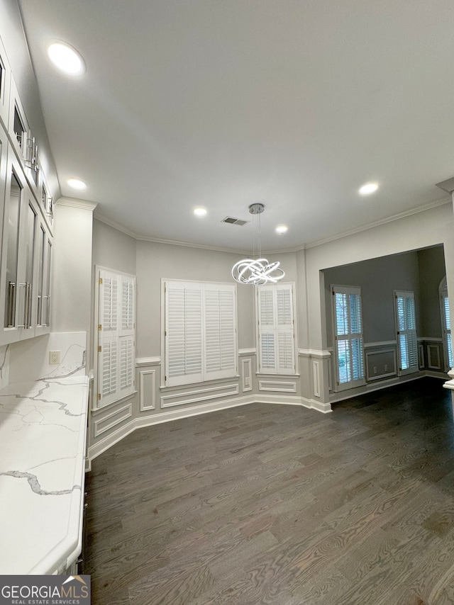 unfurnished dining area featuring dark hardwood / wood-style floors, a chandelier, and crown molding