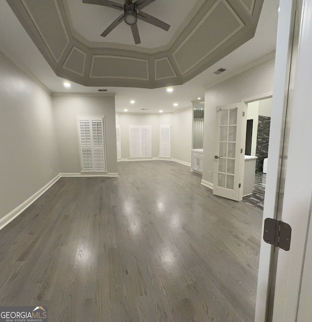 spare room with ornamental molding, ceiling fan, a tray ceiling, and wood-type flooring