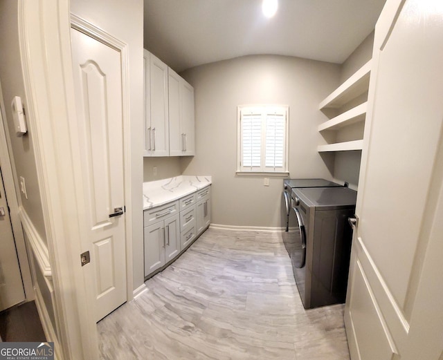 laundry room with washing machine and dryer, cabinets, and light wood-type flooring