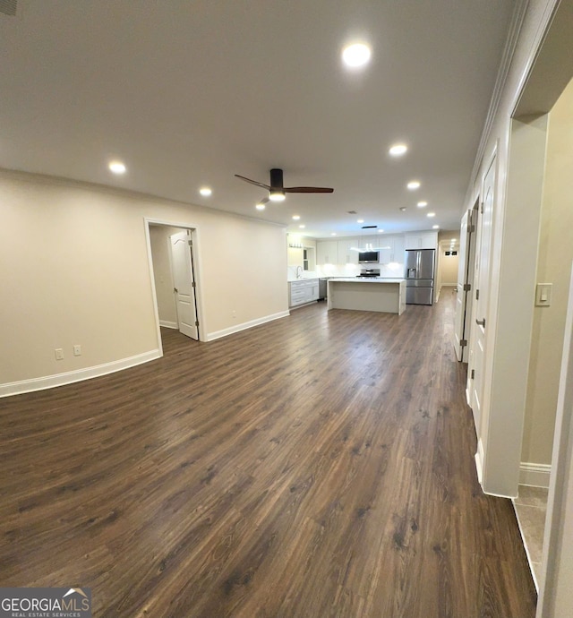 unfurnished living room featuring ornamental molding, ceiling fan, and dark hardwood / wood-style floors