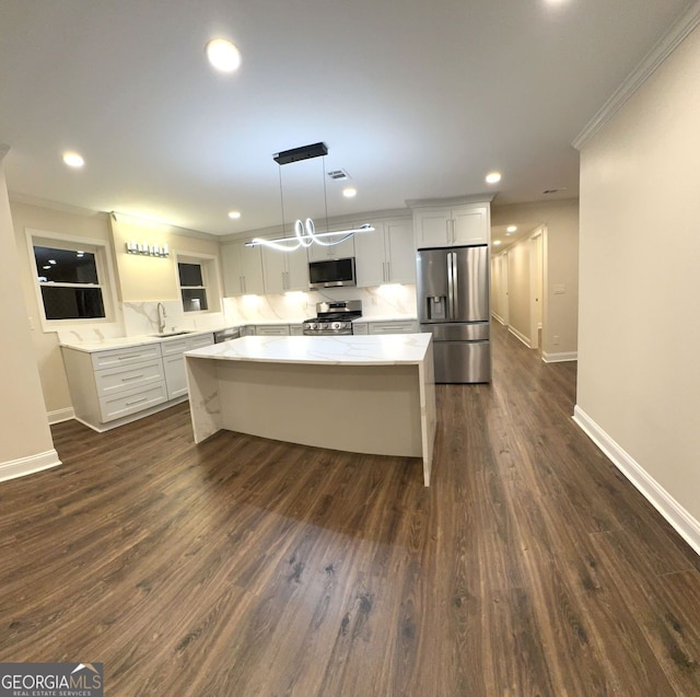 kitchen featuring dark wood-type flooring, hanging light fixtures, white cabinets, and appliances with stainless steel finishes