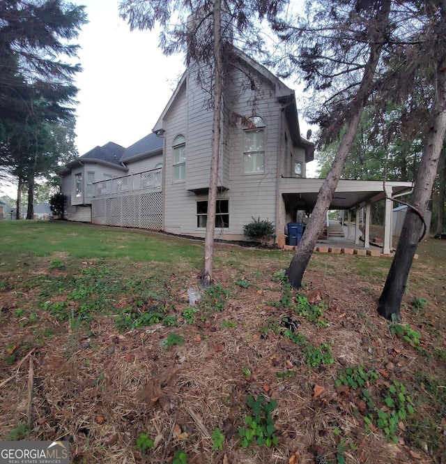 view of side of home featuring a carport and a lawn