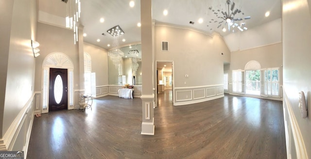 entrance foyer with decorative columns, high vaulted ceiling, an inviting chandelier, and dark hardwood / wood-style floors