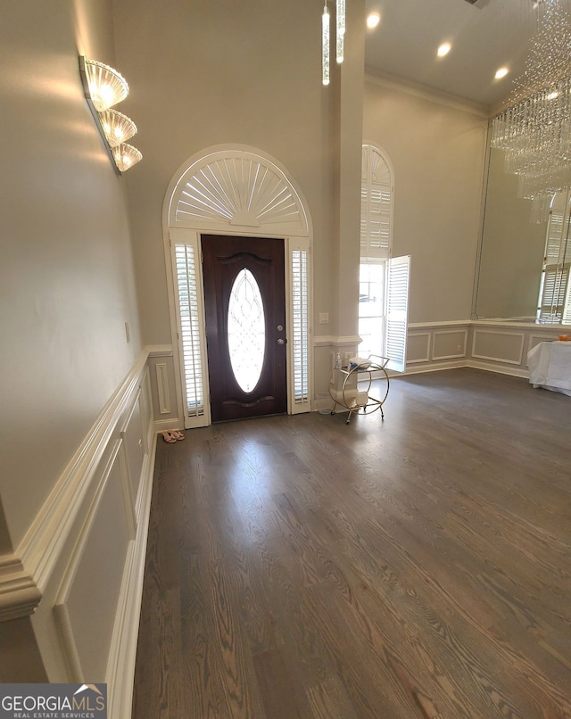 foyer with ornamental molding, a notable chandelier, and dark hardwood / wood-style flooring