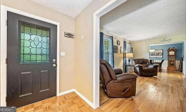 foyer entrance featuring a textured ceiling and light wood-type flooring