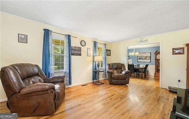 living room featuring a textured ceiling, light wood-type flooring, and a notable chandelier