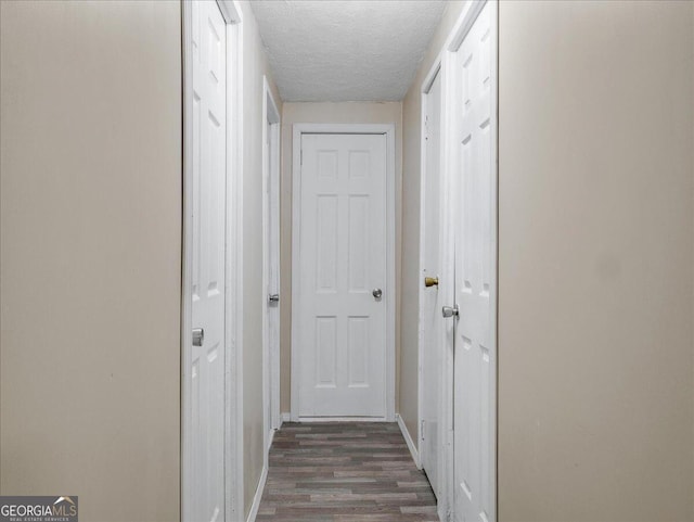 hall featuring a textured ceiling and dark hardwood / wood-style flooring