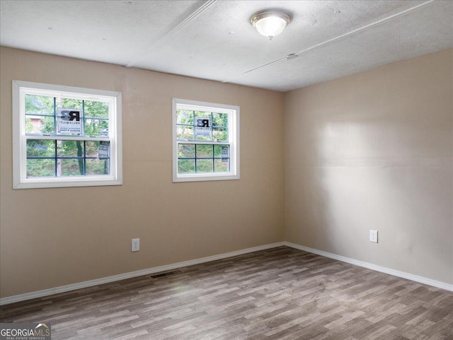 unfurnished room featuring light hardwood / wood-style flooring and a textured ceiling