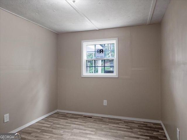 unfurnished room featuring a textured ceiling and light hardwood / wood-style floors