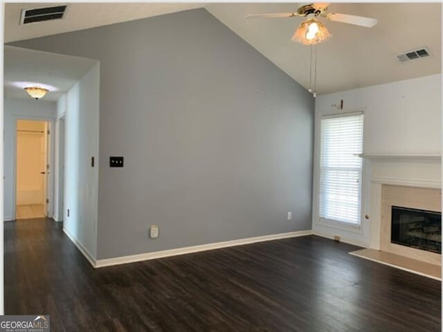 unfurnished living room featuring a fireplace, vaulted ceiling, dark hardwood / wood-style floors, and ceiling fan