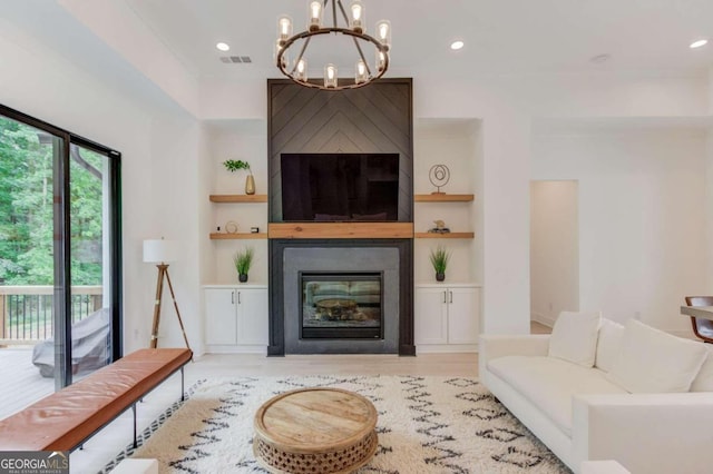 living room featuring a notable chandelier, light wood-type flooring, a fireplace, and built in features