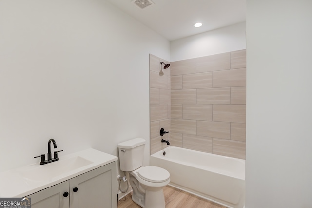 full bathroom featuring wood-type flooring, tiled shower / bath combo, vanity, and toilet