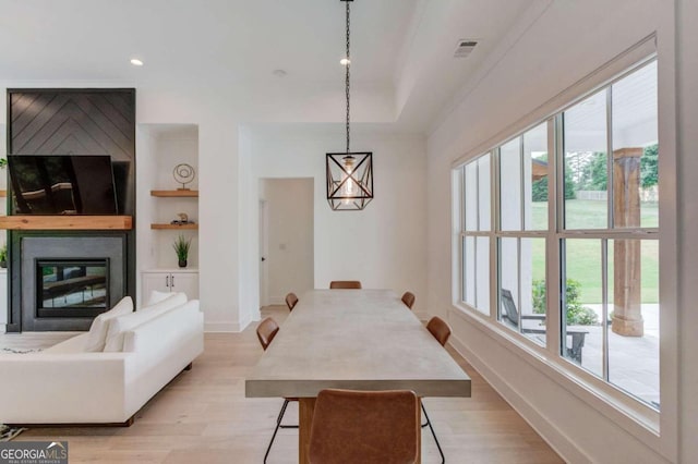 dining space featuring light hardwood / wood-style flooring, built in features, and a healthy amount of sunlight