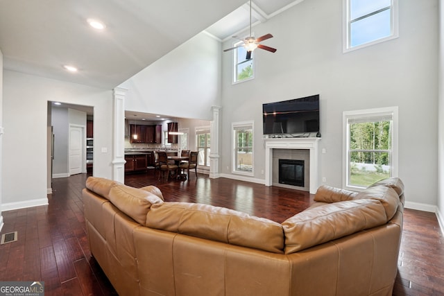 living room with a tile fireplace, a healthy amount of sunlight, a high ceiling, and dark hardwood / wood-style flooring