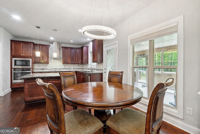 dining space with a notable chandelier, dark hardwood / wood-style floors, and sink