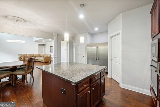 kitchen with light stone countertops, a center island, dark hardwood / wood-style flooring, and ornate columns