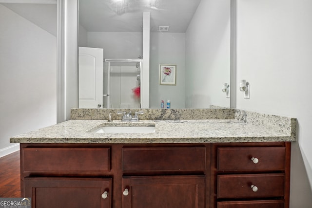 bathroom with wood-type flooring, vanity, and a shower with door