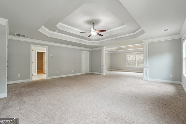 carpeted spare room with ornamental molding, decorative columns, a raised ceiling, and ceiling fan