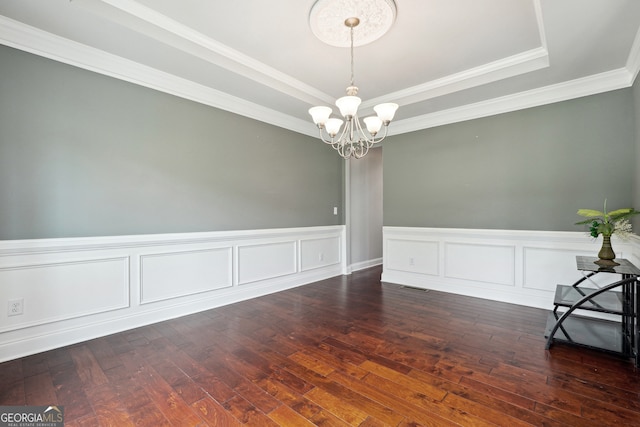 spare room featuring a raised ceiling, ornamental molding, dark hardwood / wood-style flooring, and a chandelier