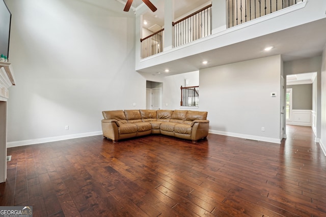 unfurnished living room featuring a towering ceiling, ceiling fan, and dark hardwood / wood-style flooring