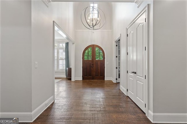 entrance foyer featuring dark wood-type flooring, a towering ceiling, and a chandelier